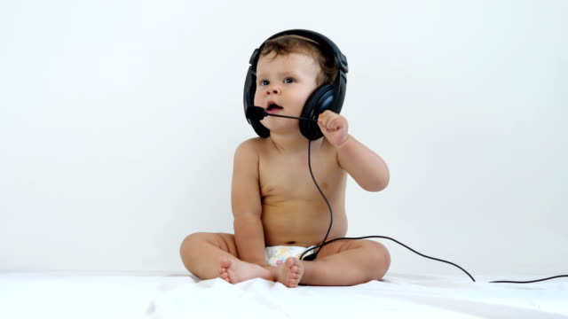 One-jährige-Kind-sitzt-und-Musik-im-Kopfhörer-hört.