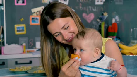 Young-mother-feeds-her-little-son-with-an-apricot