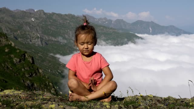 Kleine-süße-Mädchen-meditieren-auf-Berg