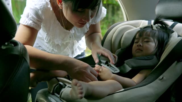 junge-schöne-asiatische-Mutter-ihre-kleine-Tochter-aus-ihrem-Autositz-Riemen