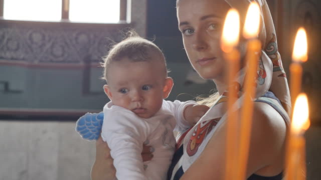 Porträt-der-jungen-Mutter-mit-kleinen-Sohn-vor-Kerzen-in-der-Kirche