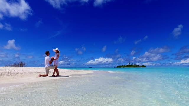 v07384-Maldivas-playa-2-personas-joven-pareja-hombre-matrimonio-mujer-propuesta-compromiso-boda-isla-paraíso-soleado-con-cielo-azul-aqua-agua-mar-4k