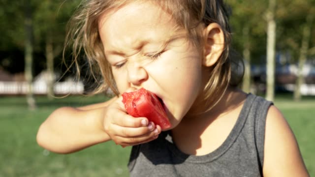 Schöne-kleine-Mädchen-essen-Wassermelone-am-Stadtpark-Sommer