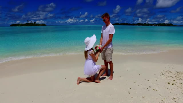v07391-Maldives-white-sandy-beach-2-people-young-couple-man-woman-proposal-engagement-wedding-marriage-on-sunny-tropical-paradise-island-with-aqua-blue-sky-sea-water-ocean-4k