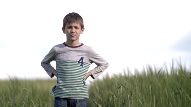 ernste-junge-Fußballer-stehen-im-Weizenfeld-in-die-Kamera-schaut