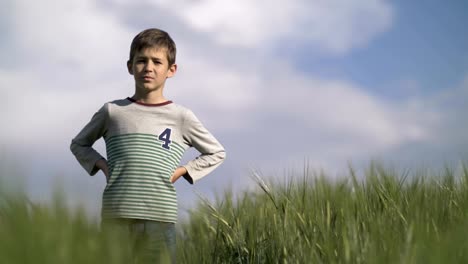 serious-boy-footballer-standing-in-the-wheat-field-looking-at-the-camera