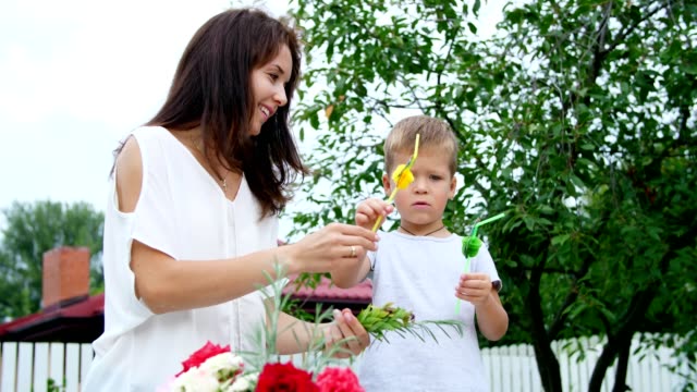 summer,-in-the-garden,-slow-motion,-Mom-with-a-four-year-old-son-decorate-the-straw-for-juice.-The-boy-likes-it-very-much,-he-rejoices,-has-fun,-shows-his-tongue