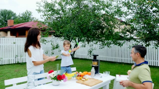 summer,-in-the-garden,-four-year-old-boy-has-decorated-the-straw-for-juice,-boasts-them-before-his-father,-mother-and-younger-sister.-The-boy-has-fun,-shows-his-tongue
