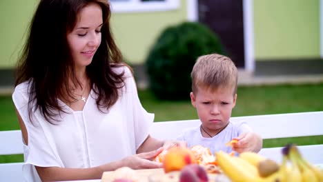 verano,-en-el-jardín.-Mamá-y-su-hijo-de-cuatro-años-de-pelan-las-naranjas.-quieren-hacer-zumo