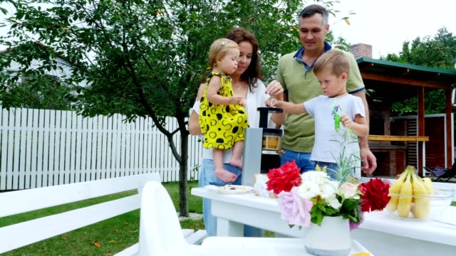 happy-beautiful-family,-mom,-dad,-four-years-old-son-and-one-year-old-daughter-make-fresh-juice-from-grapes.-In-summer,-in-garden.-family-spends-their-leisure-time-together