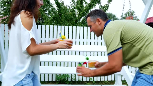 summer,-in-the-garden,-parents,-mom-and-dad,-carry-freshly-squeezed-fruit-juice-to-treat-their-children.-The-family-spends-their-leisure-time-together