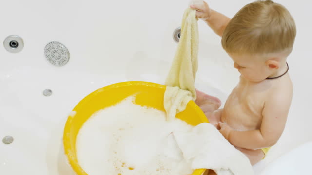 Niño-lindo-juega-con-las-toallas-en-el-baño