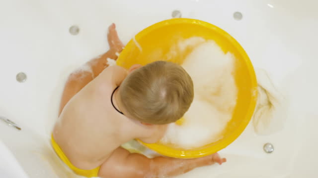 Adorable-boy-splashes-water-in-the-basin-in-bath