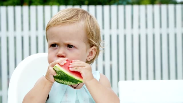 Sommer-in-den-Garten,-lustige-One-jährige-blonde-Mädchen-Wassermelone-essen