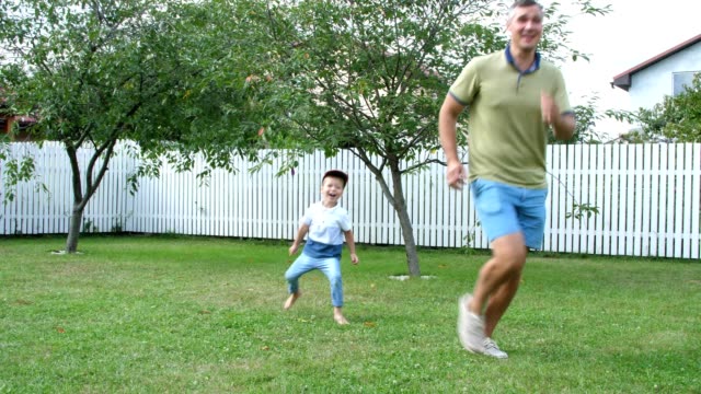 Papa-mit-einem-vier-jährigen-Sohn,-Ballspiele,-Fußball,-auf-dem-Hof-auf-einer-grünen-Wiese-im-Sommer