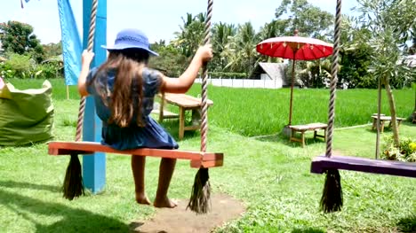 Europäische-Mädchen-spielen-Holzschaukel-mit-Glück.-Asien,-Bali.-Indonesien