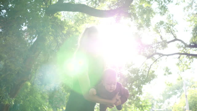 Mutter-mit-Baby-viel-Spaß-mal-auf-Hintergrund-grüne-Bäume-im-Park,-glückliche-Familie-Rest