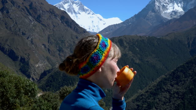 Una-niña-está-bebiendo-té-en-las-montañas
