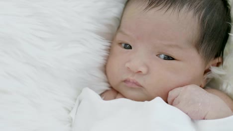 4K-Nahaufnahme-von-asiatisches-Baby-auf-einer-weichen-Decke-verlegen