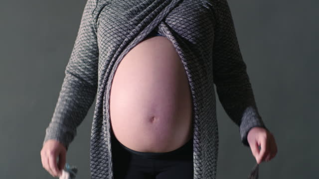 Mamá-embarazada-mostrando-desnudo-vientre-acoge-la-imagen-de-ultrasonido-con-bebé-botines-cerrar-vista-anunciando-su-embarazo-foto-ejemplo-de-la-maternidad