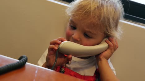 Baby-Telefon-an-das-Ohr-halten.-Kleinkind-hält-Telefon-neben-Ohr-hören,-jemand-auf-der-anderen-Leitung-in-4-K