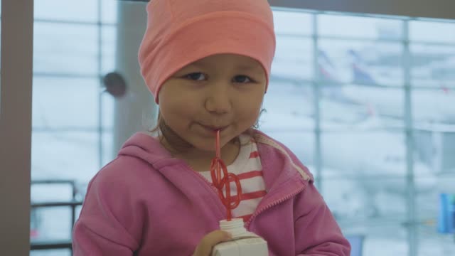 Portrait-of-a-little-child-drinking-juice-and-looking-into-the-camera-at-airport