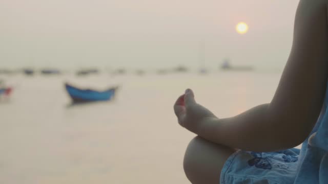 Kleine-süße-Mädchen-meditiert-in-türkischen-Pose-am-Meer
