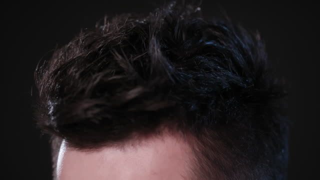 Mann-berühren-seine-Haare-gegen-ein-schwarzer-Hintergrund