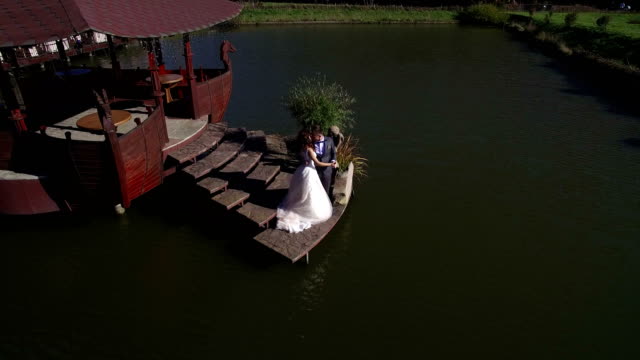 Vista-aérea.-Felices-son-las-novias-en-un-día-soleado-en-un-puente-cerca-del-lago