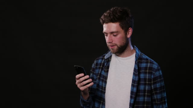 Ein-Mann-mit-einem-Handy-vor-schwarzem-Hintergrund