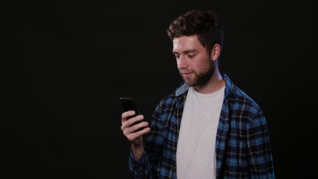 A-Man-Using-a-Phone-Against-a-Black-Background