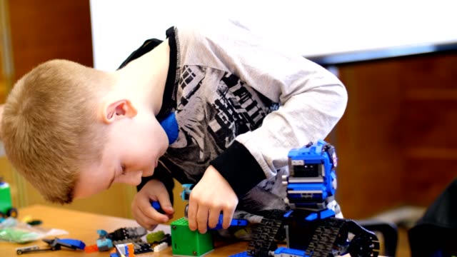 el-niño-de-10-años,-juega-en-el-diseñador-de-cubos,-placas,-circuitos,-cables.-un-pequeño-inventor-crea-robots,-máquinas-de-diferentes-partes-del-diseñador.-los-niños-son-aficionados-de-la-robótica,-programación,-modelado