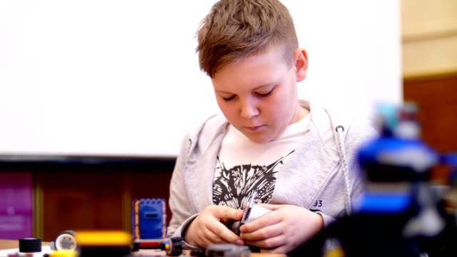el-niño-de-11-años,-juega-en-el-diseñador-de-cubos,-placas,-circuitos,-cables.-un-pequeño-inventor-crea-robots,-máquinas-de-diferentes-partes-del-diseñador