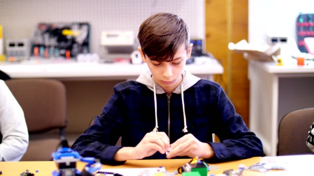 der-junge-von-12-Jahren,-spielt-in-der-Designer-aus-Würfel,-Drähte,-Platten,-Schaltungen.-ein-kleine-Erfinder-schafft-Roboter,-Maschinen-aus-verschiedenen-Teilen-des-Designers
