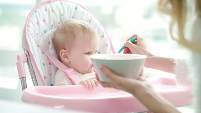 Mutter-Fütterung-Kind-mit-Babynahrung.-Kleinkind-Mädchen-essen-pürierte-Nahrung