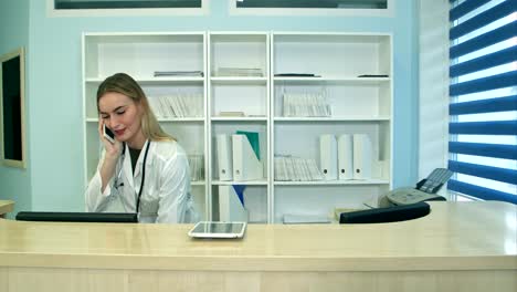 Female-nurse-at-hospital-reception-answering-phone-calls-and-scheduling-patient-appointments
