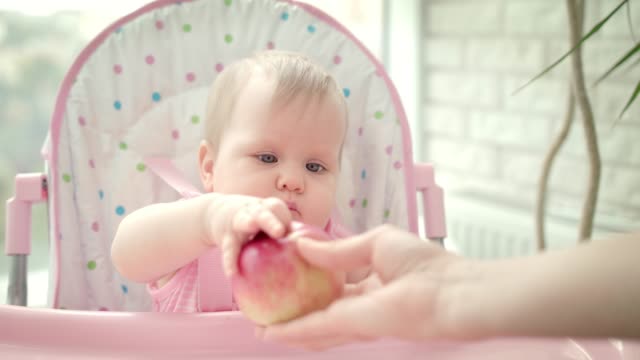 Schöne-Baby-essen-Apfel-im-Kinderstuhl.-Nettes-Kind-Obst-schmecken