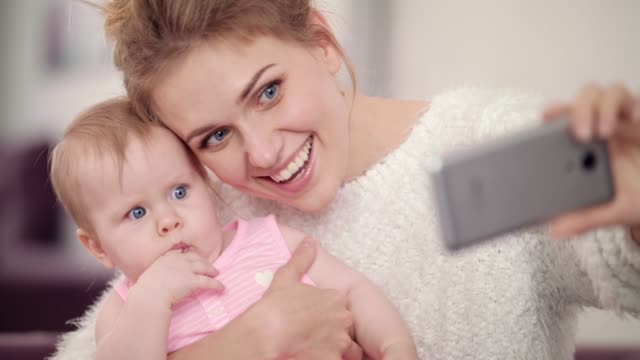 Foto-de-selfie-haciendo-del-sonriente-madre-con-bebé.-Mujer-con-foto-móvil-chico
