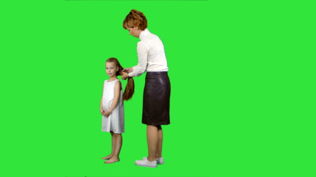 Madre-feliz-haciendo-el-estilo-de-pelo-para-una-hija-en-una-pantalla-verde-Chroma-Key