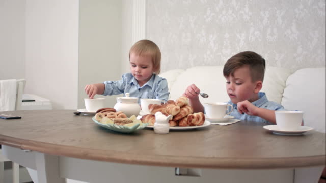 Dos-chicos-tomando-té-con-pasteles-en-la-mesa