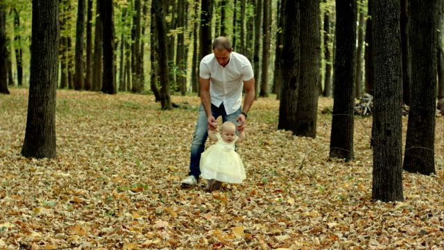 Padre-y-su-bebé-que-el-primer-paso-en-otoño-parque