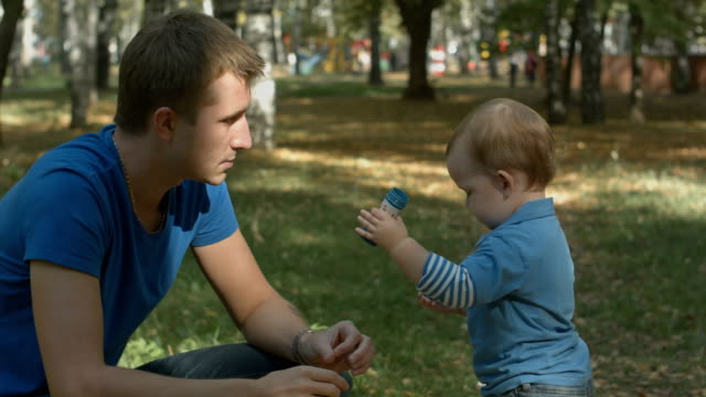 Little-baby-boy-taking-bubbles-from-father-and-walks-away