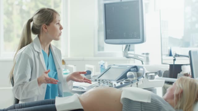 En-el-Hospital,-mujer-embarazada-obtener-ecografía-/-ultrasonido-de-detección-/-escaneo,-obstetra-comprueba-la-imagen-del-bebé-saludable-en-la-pantalla-del-ordenador.-Médico-explica-detalles-de-la-imagen.