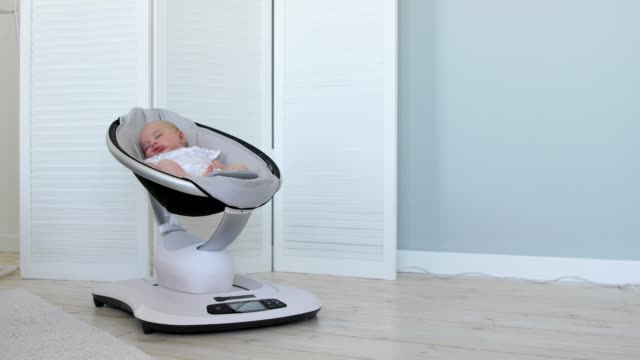 Süßes-Neugeborenes-Mädchen-schläft-in-einem-Türsteher-Stuhl-in-einem-weißen-Raum