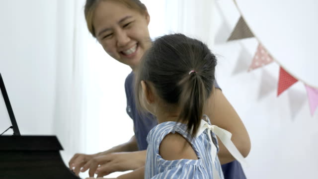 4K-:-Slow-motion-of-Asian-girl-playing-piano-with-her-mother