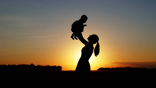 Silhouette-der-Mutter-mit-Kind-bei-Sonnenuntergang