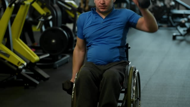Hombre-en-silla-de-ruedas-de-entrenamiento-con-pesas-en-gimnasio