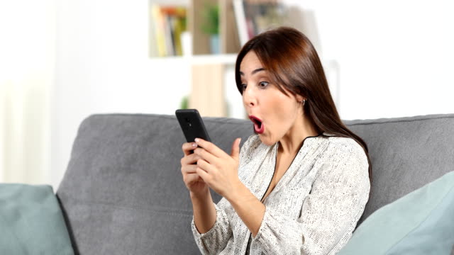 Surprised-woman-reading-phone-content-at-home