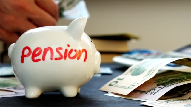 Pension-written-on-a-piggy-bank-and-hands-counting-money.-Retirement-planning.