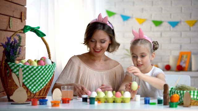 Beautiful-mother-and-daughter-packing-dyed-Easter-eggs-into-box-high-fiving